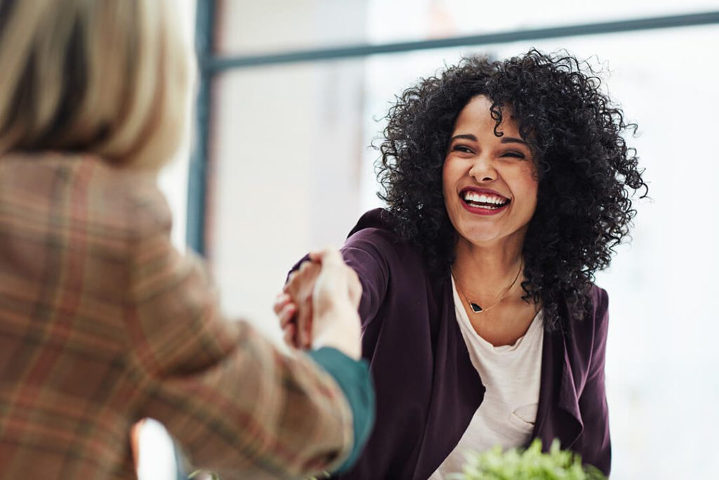 Two professional women shaking hands in a business setting